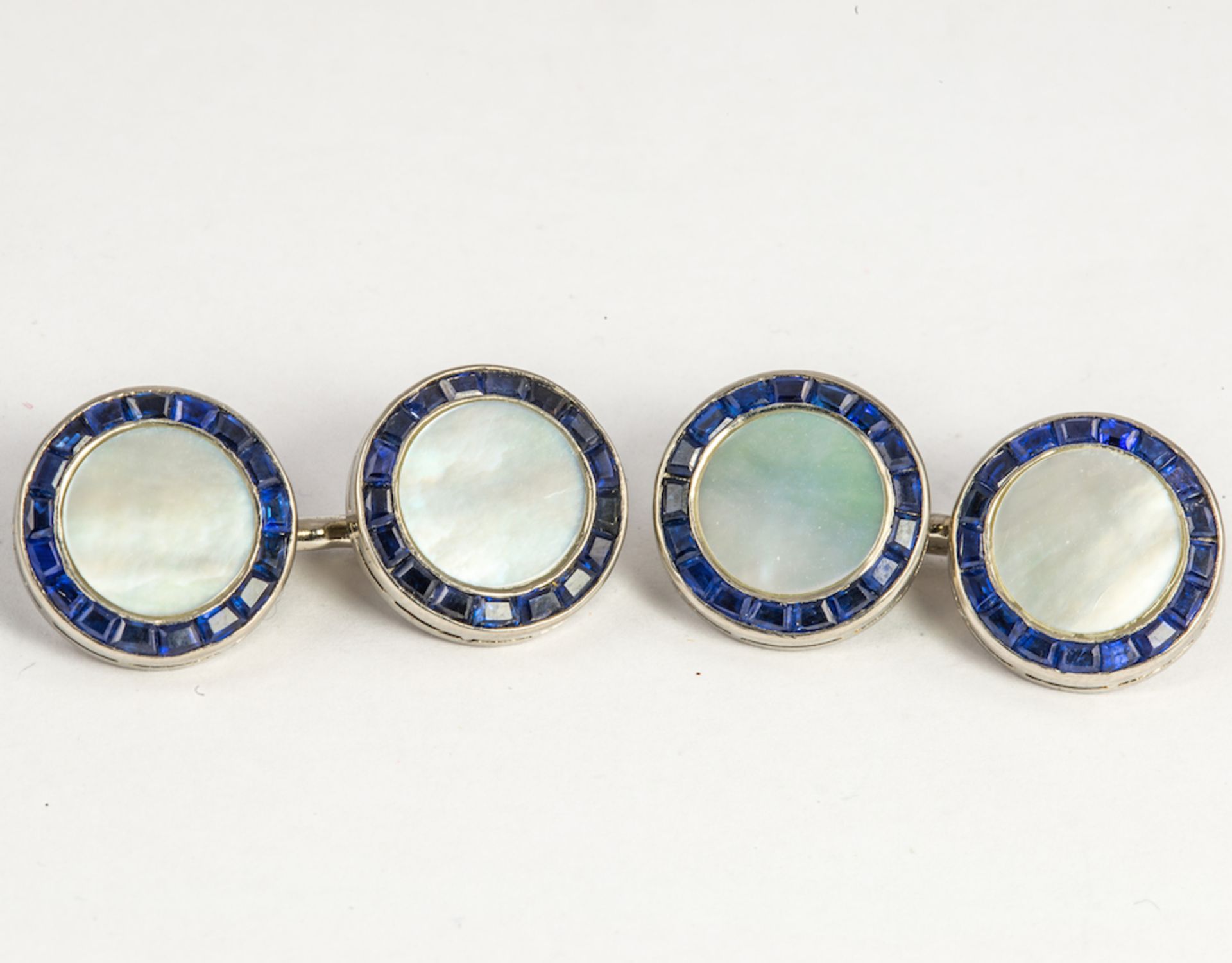 CARTIER - a pair of mother of pearl, caliber-cut sapphire cufflinks, signed and numbered Cartier