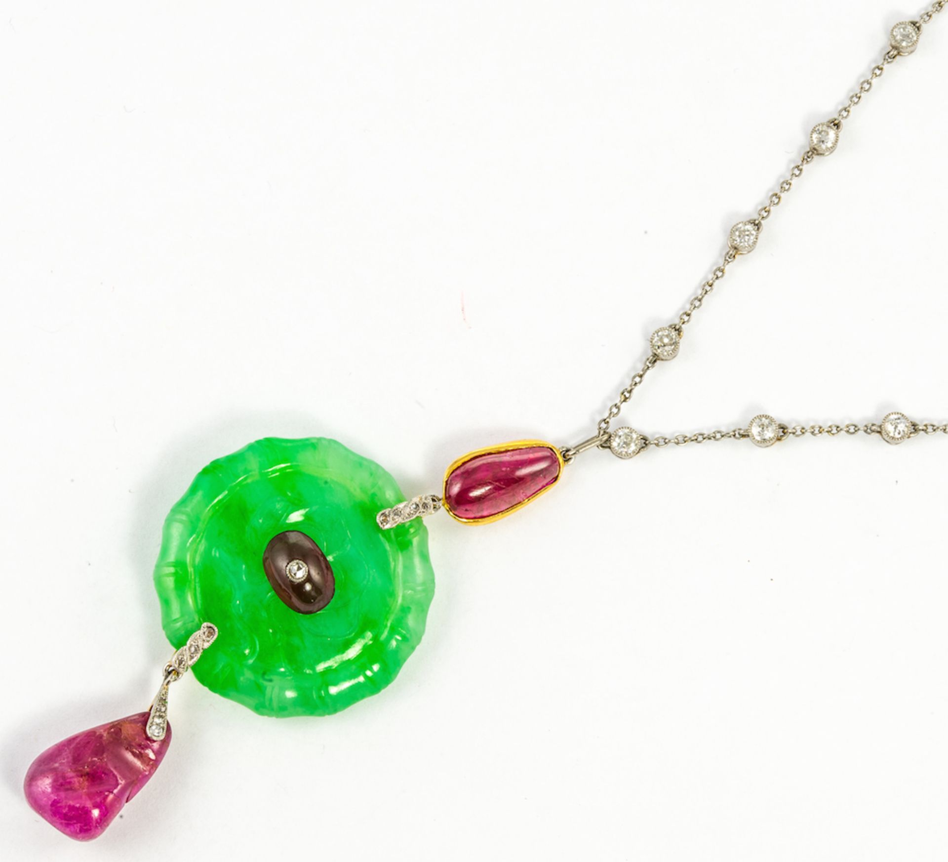 CARTIER NEW YORK - a Ruby, jadeite and diamond pendant c.1920, the circular jadeite plaque carved