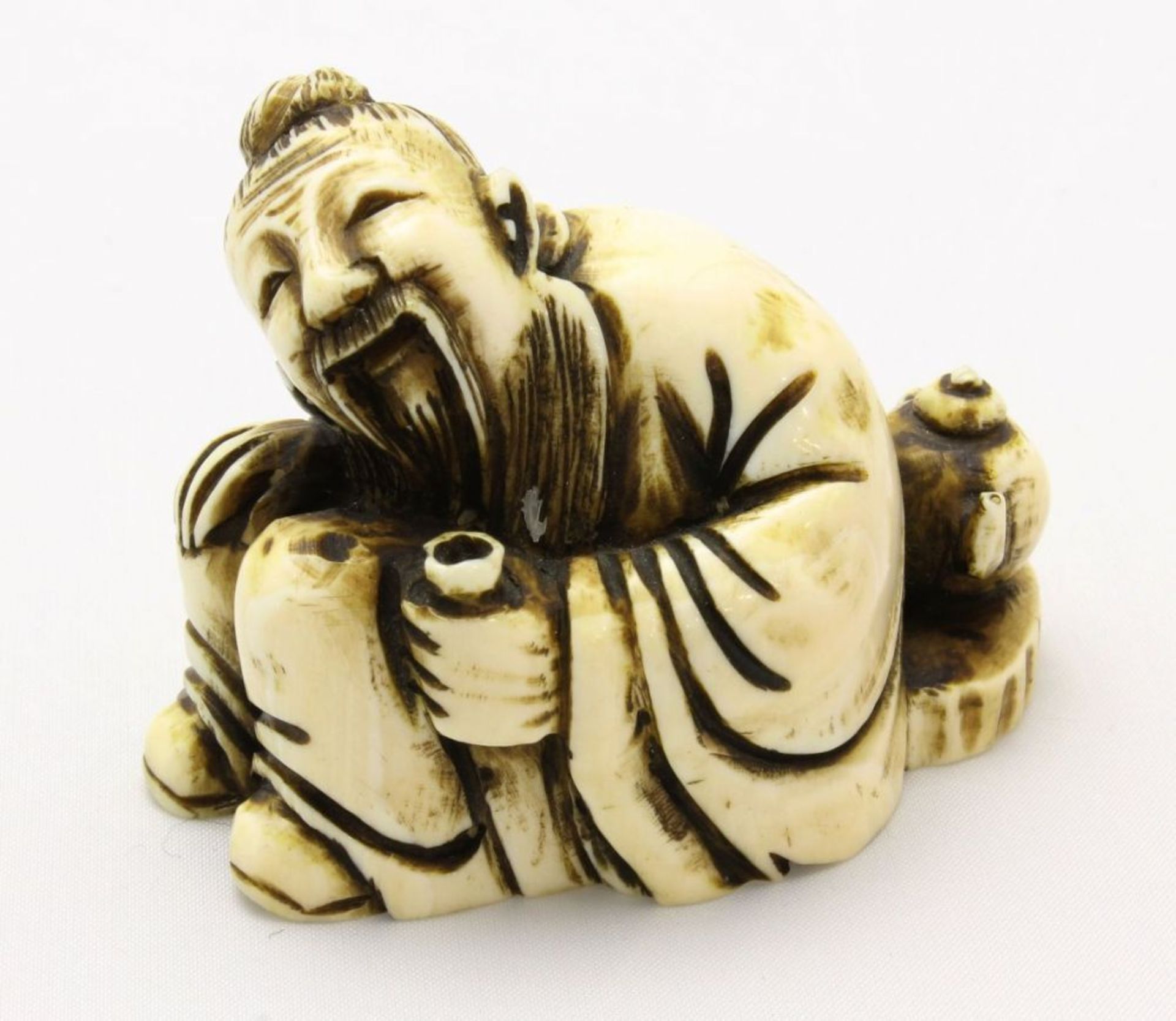 Netsuke  Elfenbeinfigur eines Mannes, am Boden sitzend mit Teekanne hinter dem Rücken, fein