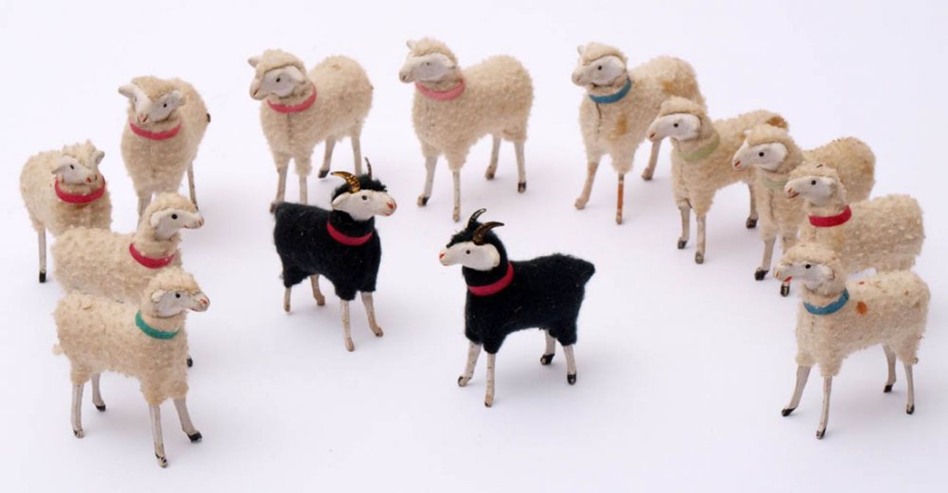 Elf Schafe und zwei Ziegenböcke, um 1900 Holz und Wolle, Köpfe aus Masse. H. ca. 7cm.