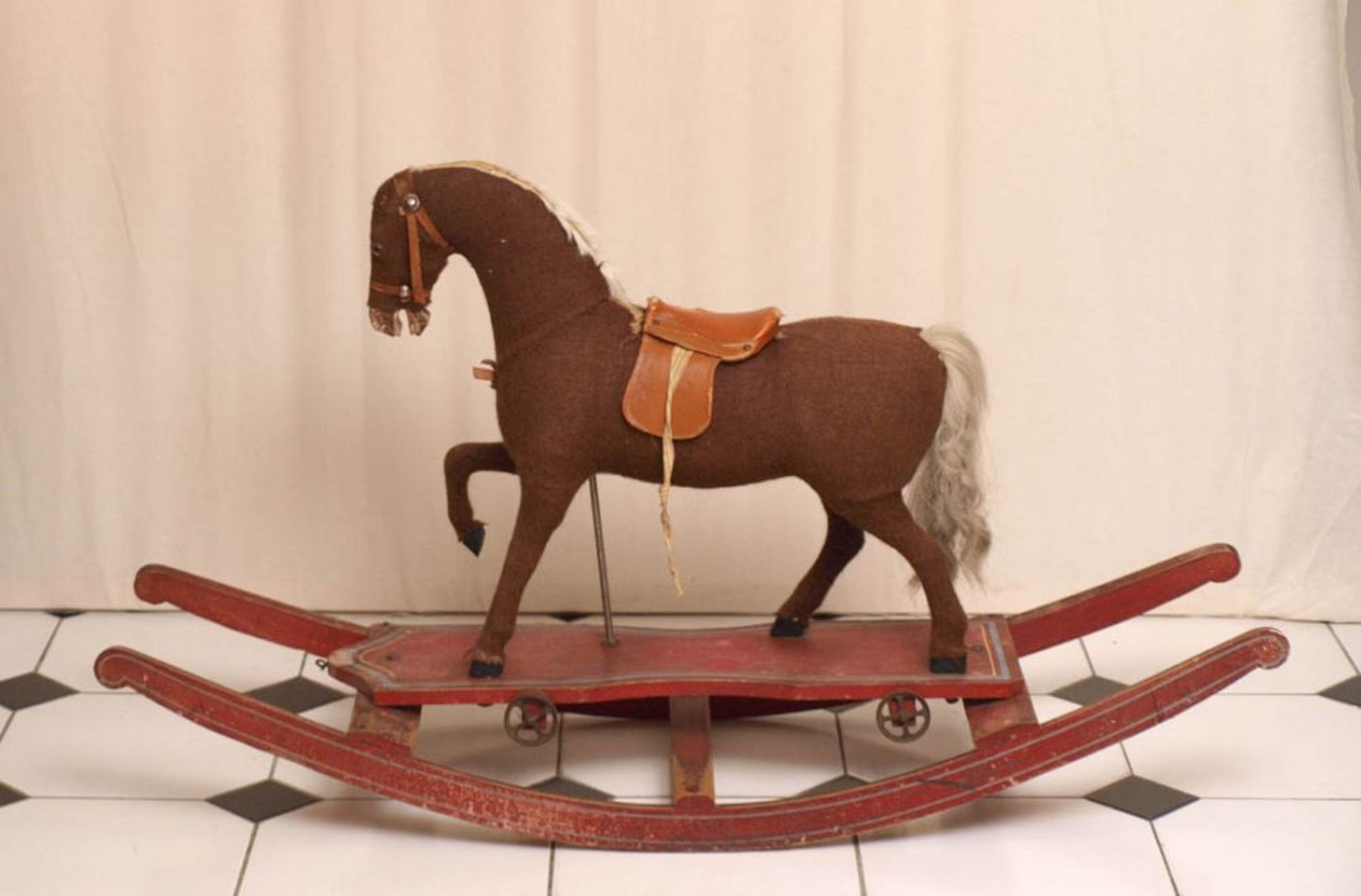 Schaukelpferd, um 1900 Auf bewegtem Sockelbrett mit Eisenrädern hölzerner Pferdekörper mit