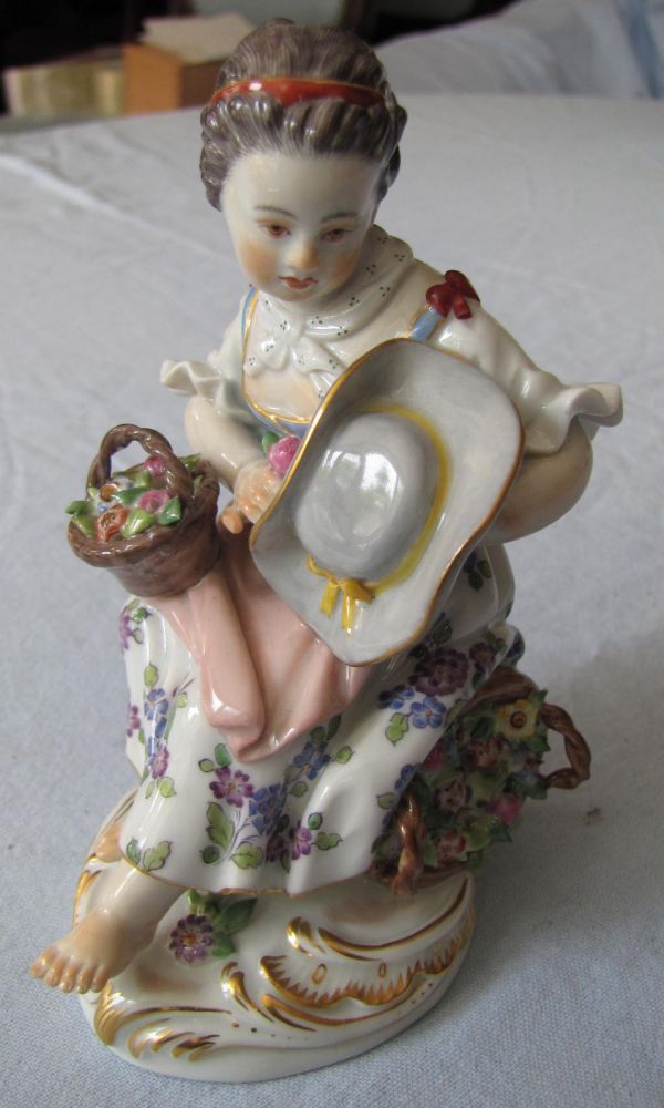Porcelain Figurine, Meissen. Girl sitting on colorful flower basket.  11.5 cm high. First choice.