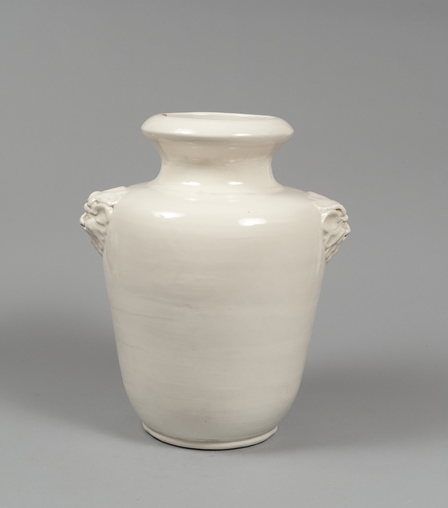 CERAMIC VASE, MANUFACTURE OF THE 80S  entirely in white enamel, with handles in the lions` heads.