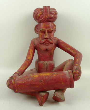An Indian red painted wooden carving of a seated drum player, 39cm high.