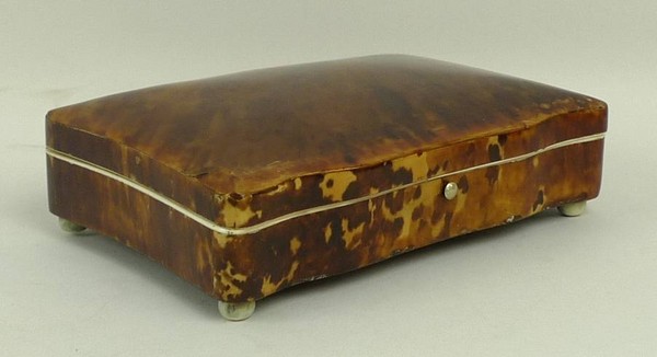 A 19th century tortoiseshell box with shaped front and sides, ivory lined edges and bun feet, 15