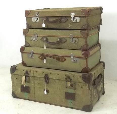 Five green canvas and leather suitcases, one labelled for Papworth Industries 1954, and a similar