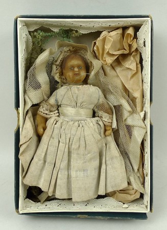 A Victorian wax doll, missing legs, fully clothed, in a fitted box, 14.5cm long.