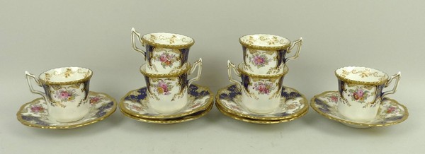 A set of six Coalport porcelain coffee cans and saucers, gilt highlighted, reserve decorated with