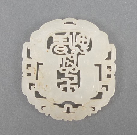 A Chinese white jade pendant carved with a pierced decoration of characters encircled by two