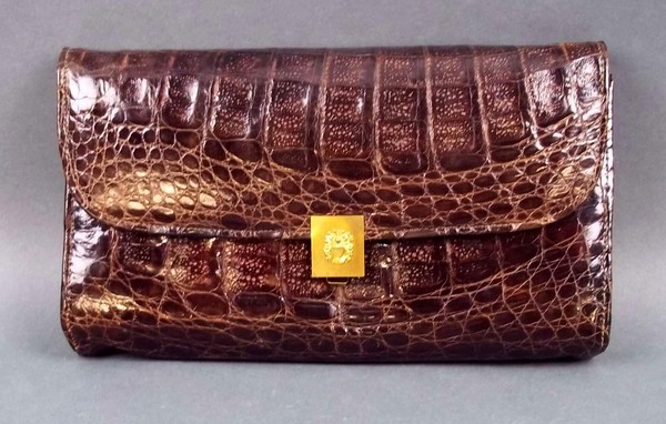 A Brazilian clutch bag with a crocodile skin exterior and brown suede interior, and a rolled gold