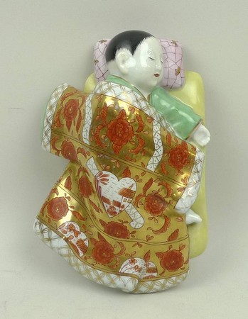 A Herend porcelain wall plaque modelled as a sleeping Chinese child, printed mark, 19 by 13 by 6cm.