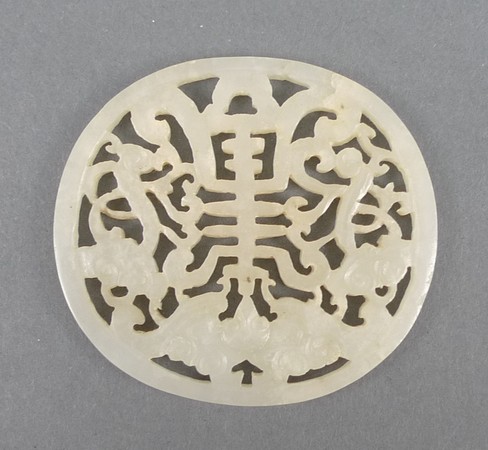 A Chinese pale celadon jade disc of pierced, oval section carved with bats, 5.5 by 5cm.