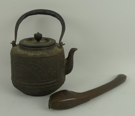 A Japanese iron tea pot, Meiji period, decorated with panels of a crab, bamboo and script, 11cm