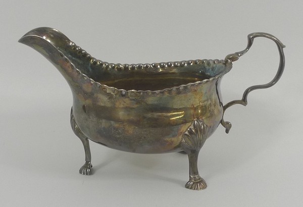 A George III silver sauce boat, repousse beading to rim, scroll handle with leaf decoration, tri