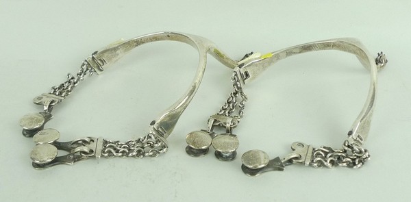 A pair of Continental, 19th century, white metal spurs of swan neck form with chain and button