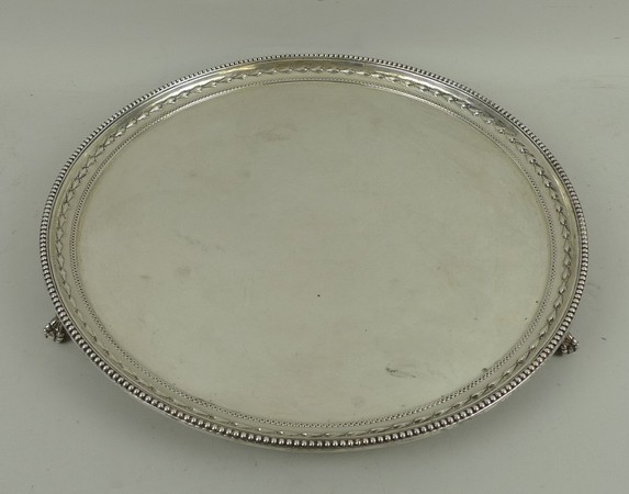 A circular silver salver embossed with a border of harebells within a beaded rim, raised on three