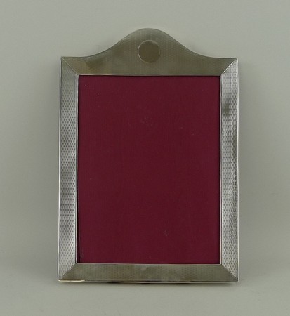 A silver strut photograph frame with engine turned decoration, London 1919, 27 by 19cm.