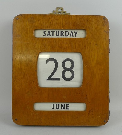 An oak cased wall mounted calendar, early 20th century, the day, date and month printed on cloth