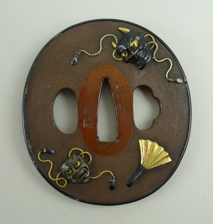 An 18th century Japanese tsuba made by Shozui, marugata shape, decorated with Noh masks in high