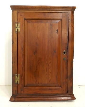 A late Georgian pitch pine corner cupboard, circa 1800, cornice over a single door with fielded