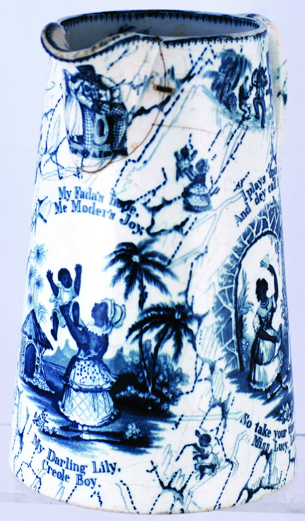 UNCLE TOM & EVA JUG. 8.5ins tall, white glaze with blue pictorial transfers featuring black people