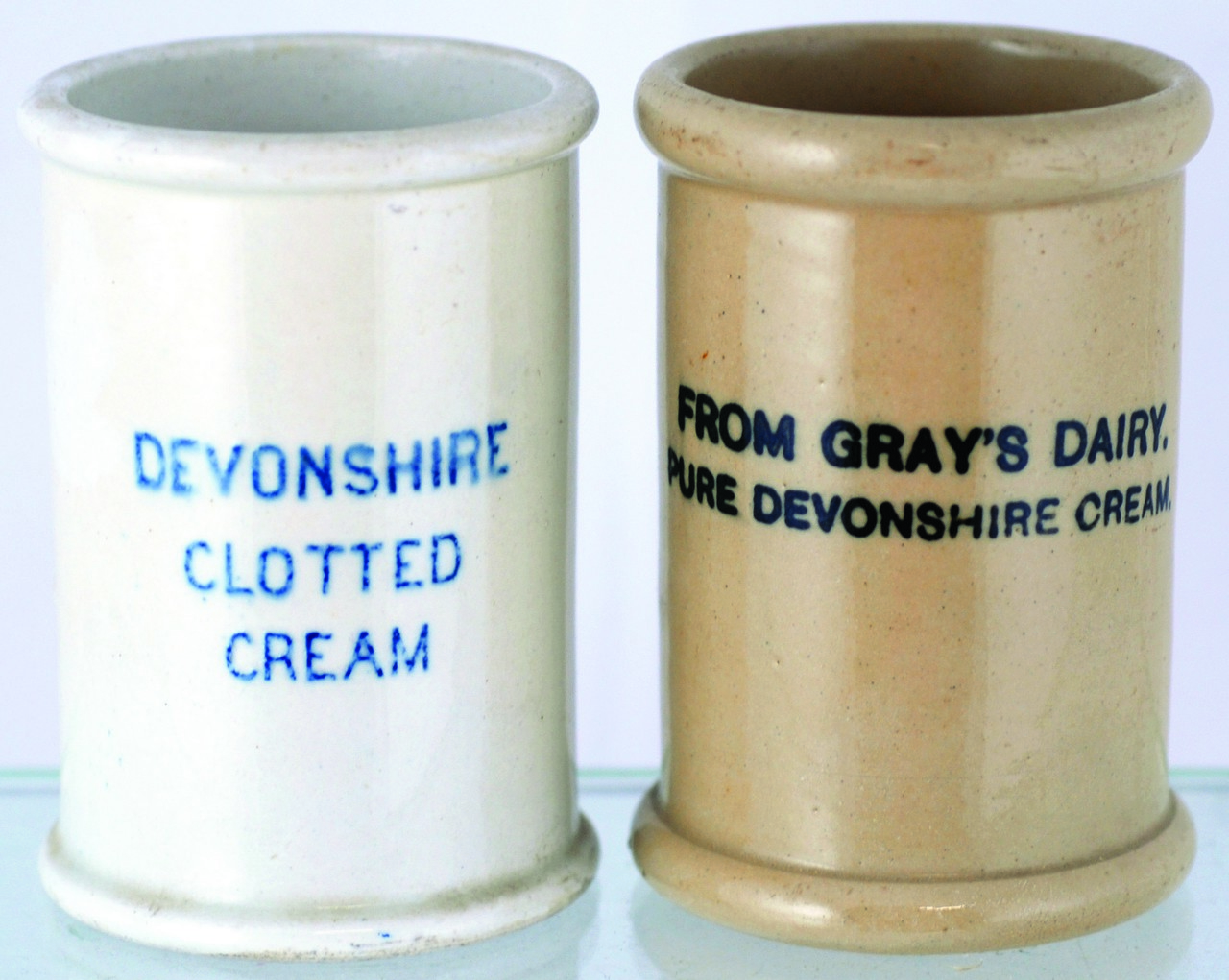 PAIR OF CYLINDRICAL CREAM POTS. 3.5ins tall, white glaze, blue print ?DEVONSHIRE/ CLOTTED/ CREAM?