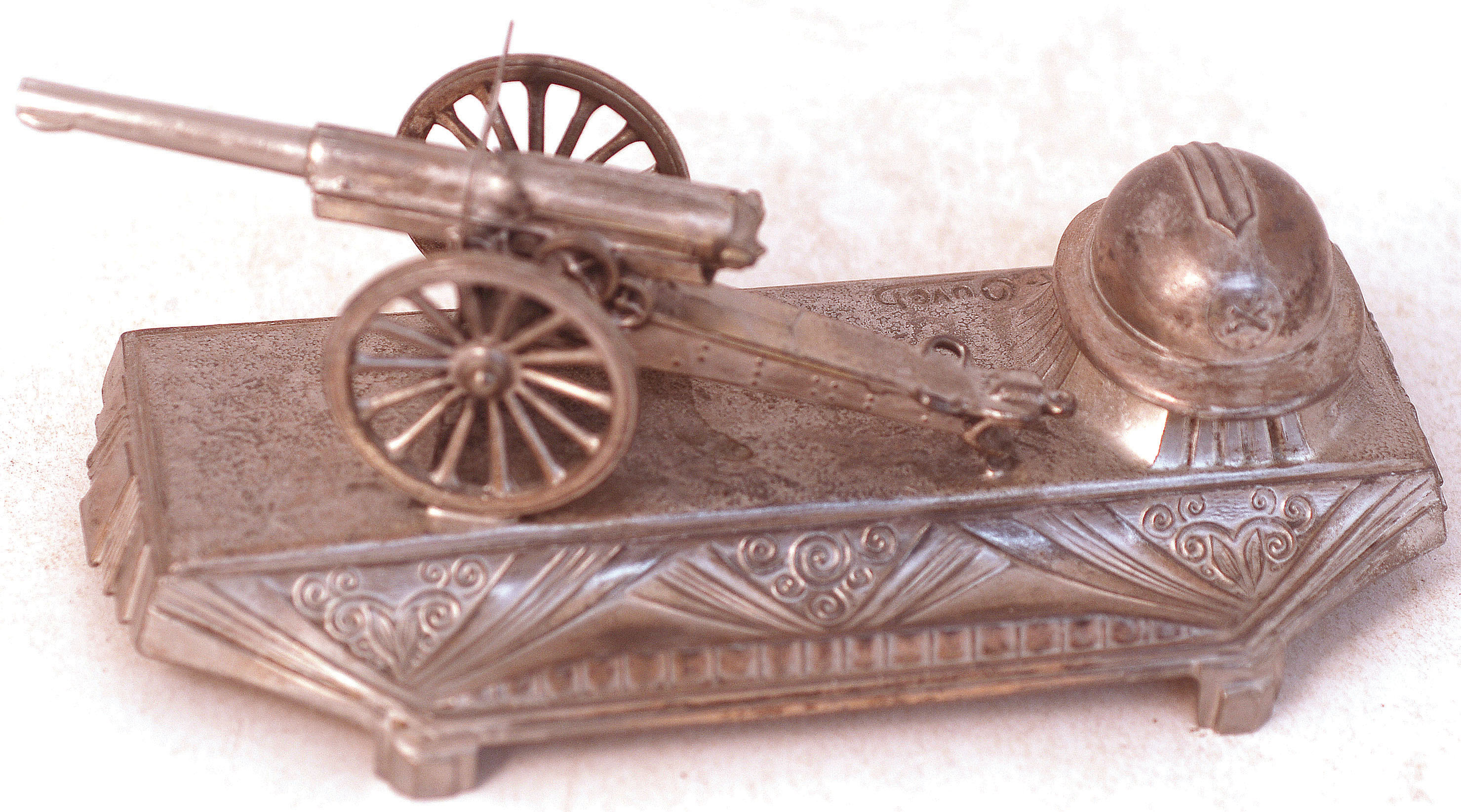 MILATARY INKSTAND. 2.25ins tall, 6.25ins long, white metal with cannon & soldiers helmet which lifts