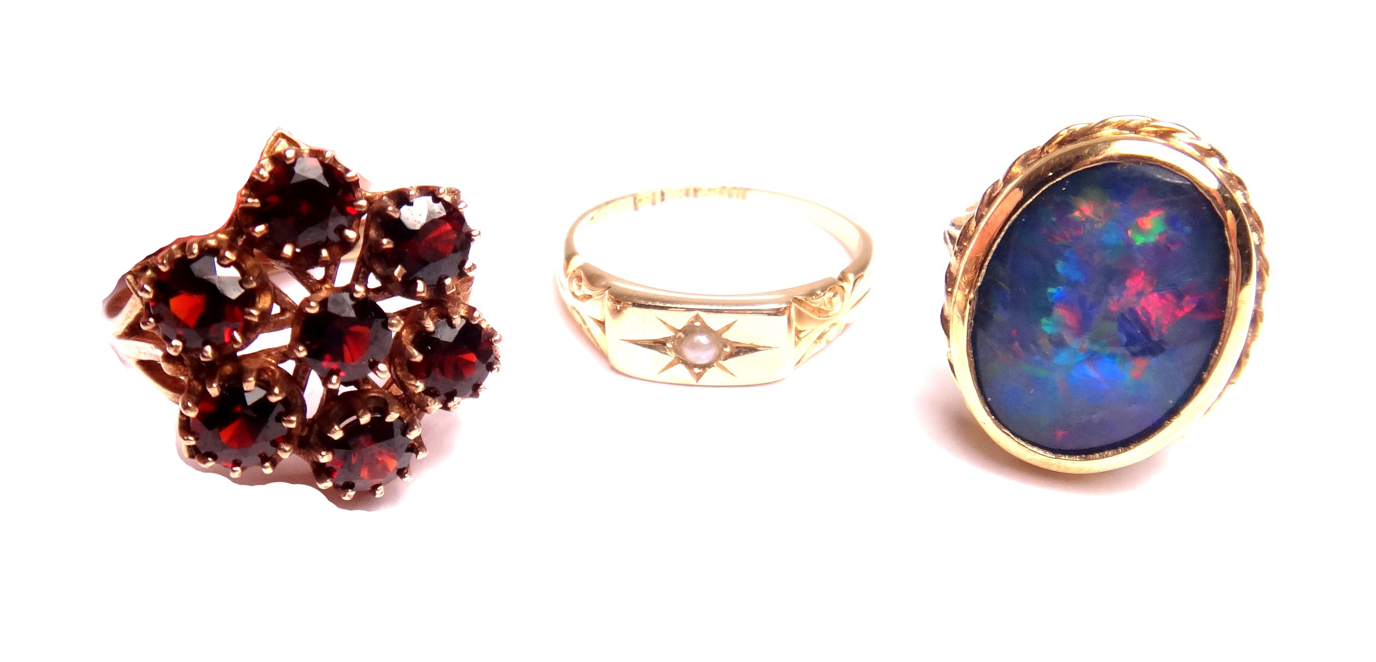 A 9ct gold ring, mounted with an oval opal doublet, a 9ct gold and garnet set seven stone cluster