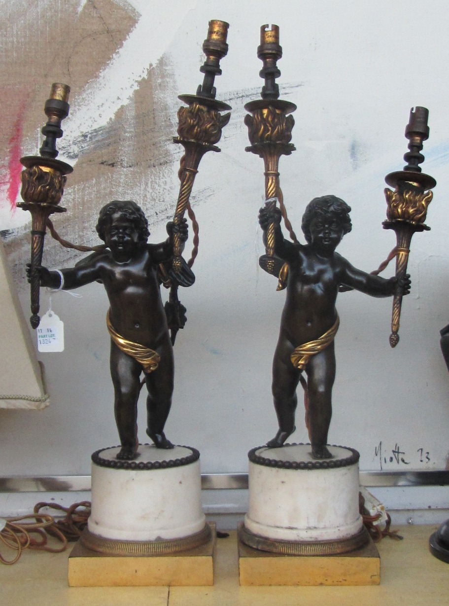 A pair of patinated bronze figural two branch table lamps, mid 19th century, the cherubic figures