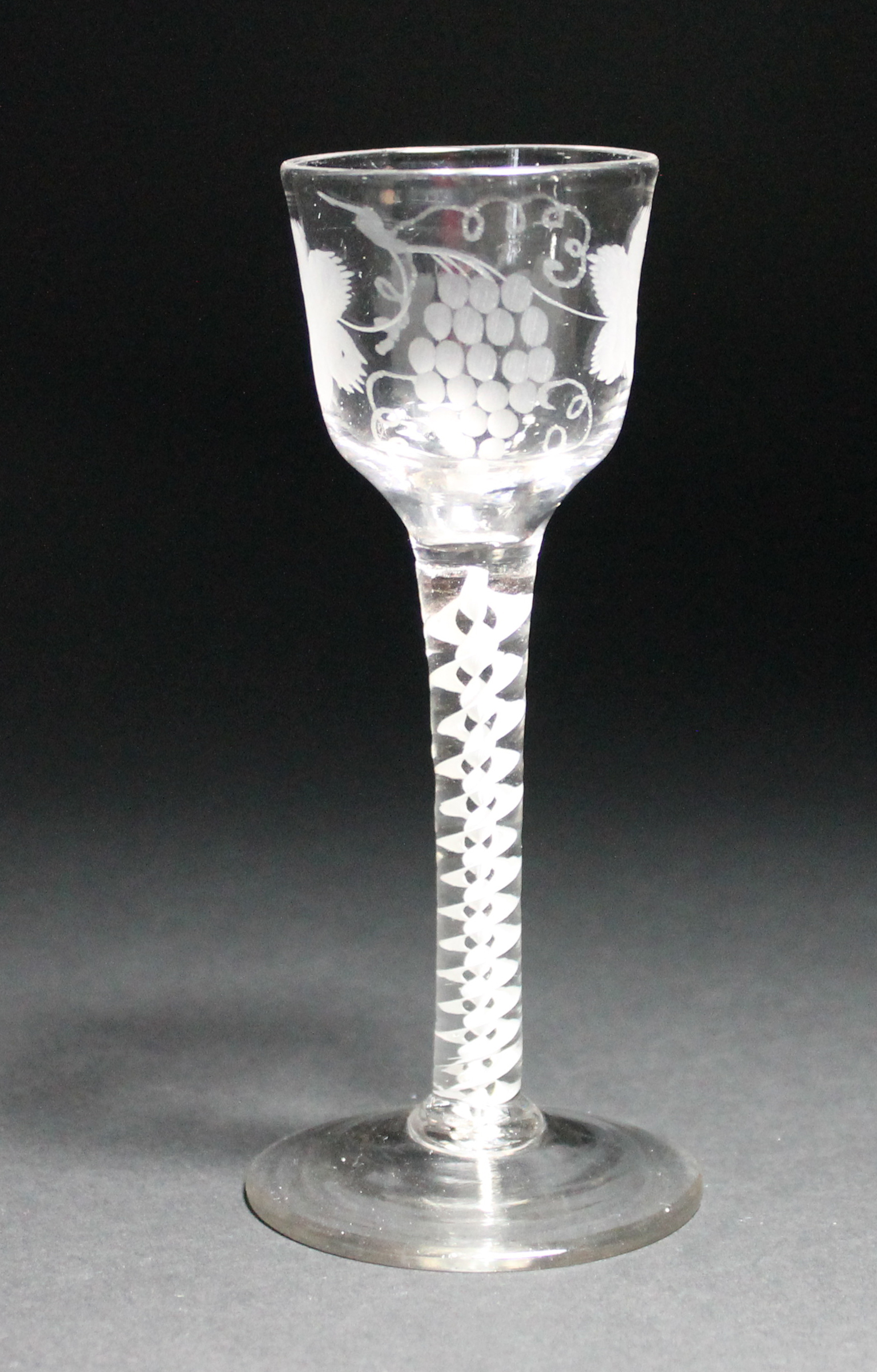 An opaque twist wine glass, circa 1765, the ogee bowl engraved with fruiting vine, raised on a
