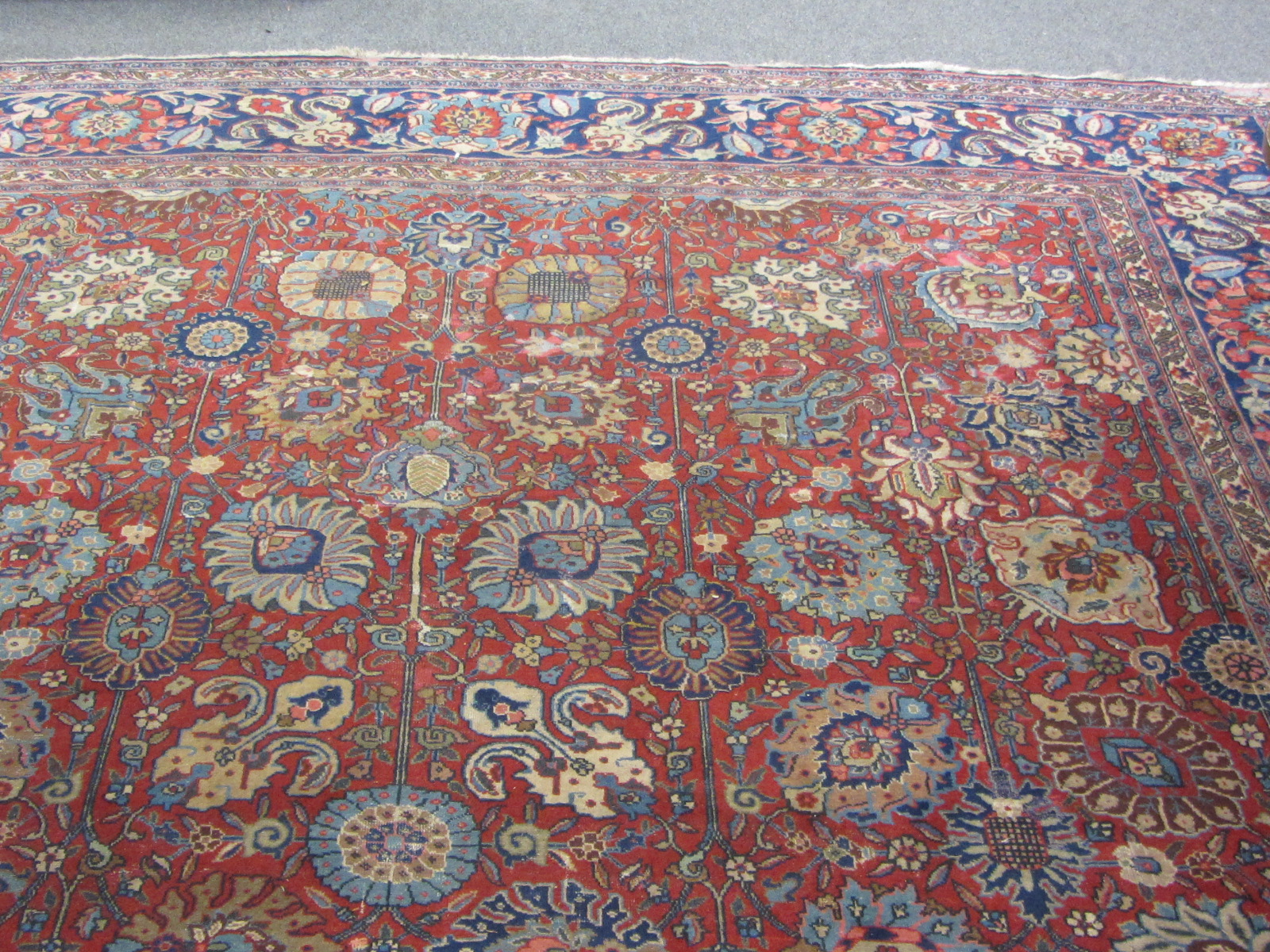 A Tabriz carpet, Persian, the madder field with an allover design of palmettes and floral sprays, an