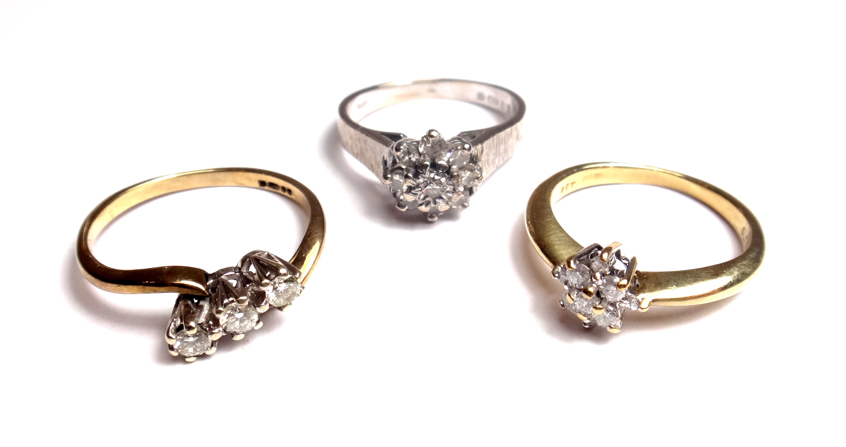 An 18ct white gold and diamond set nine stone cluster ring, with bark textured shoulders, a 9ct gold