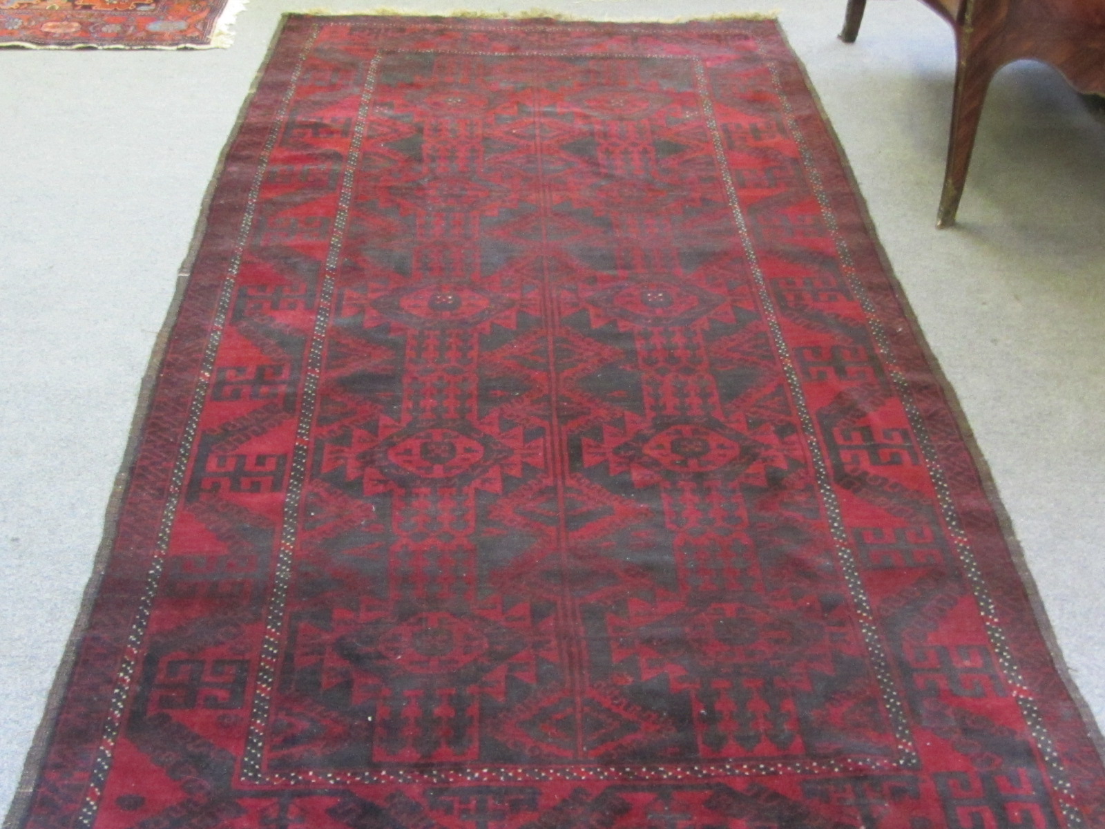 A Baluchistan rug, the madder field with a black design of two columns and diamond medallions, an