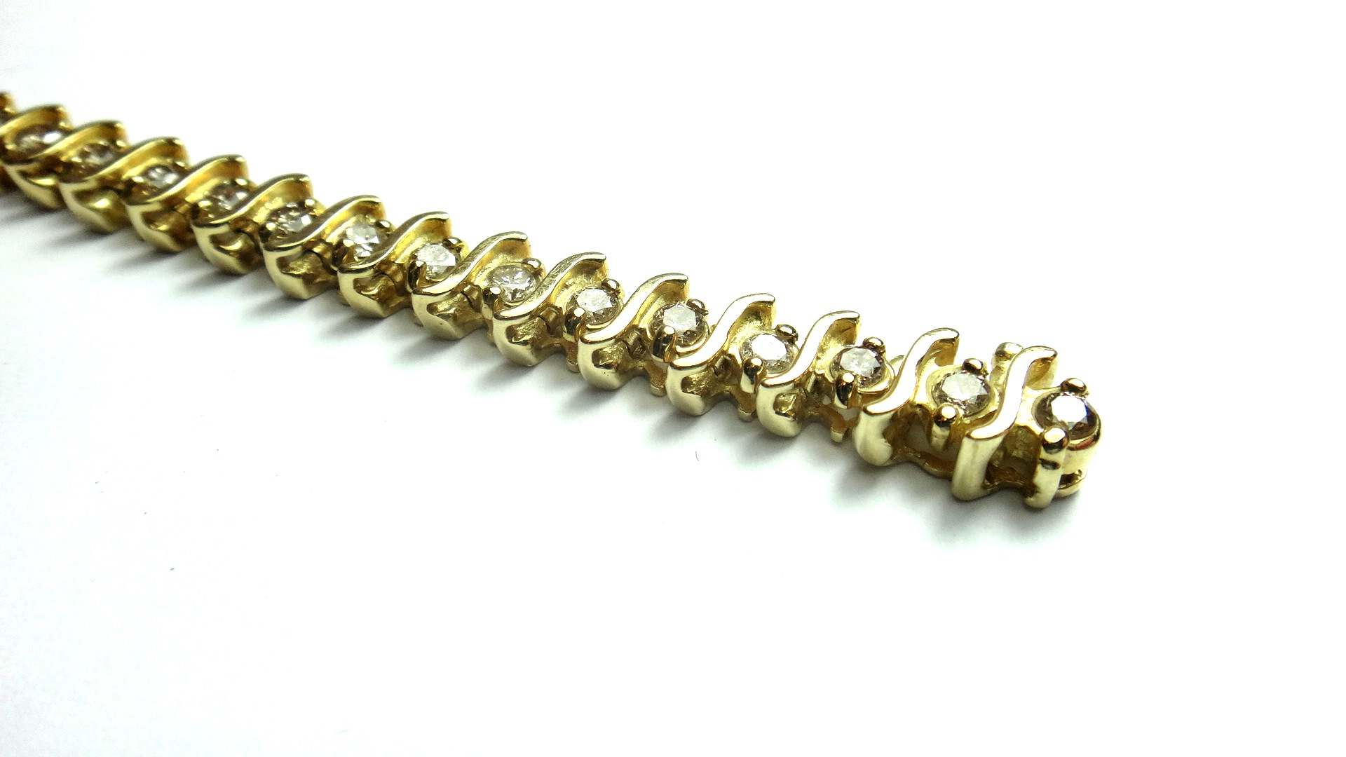 A gold and diamond set bracelet, claw set with a row of circular cut diamonds, alternating with '