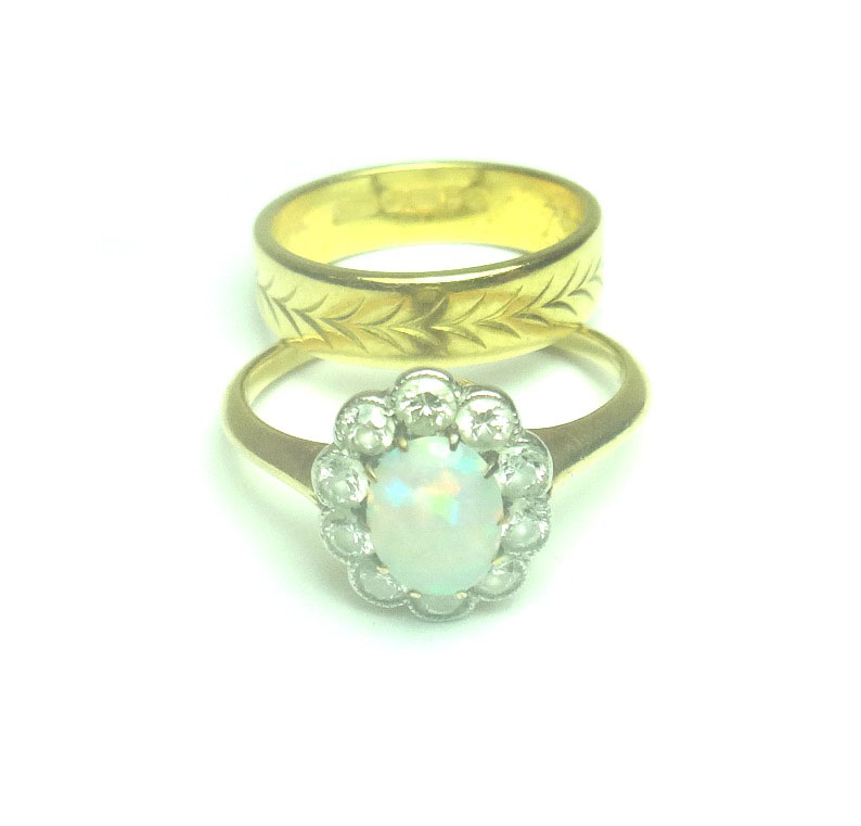 A gold, opal and diamond set oval cluster ring, claw set with the oval opal at the centre, within