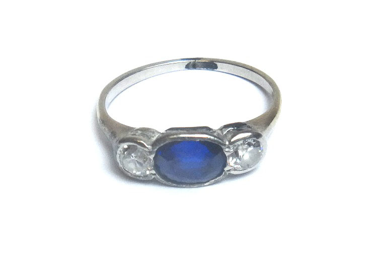 A sapphire and diamond set three stone ring, mounted with the oval cut sapphire at the centre,