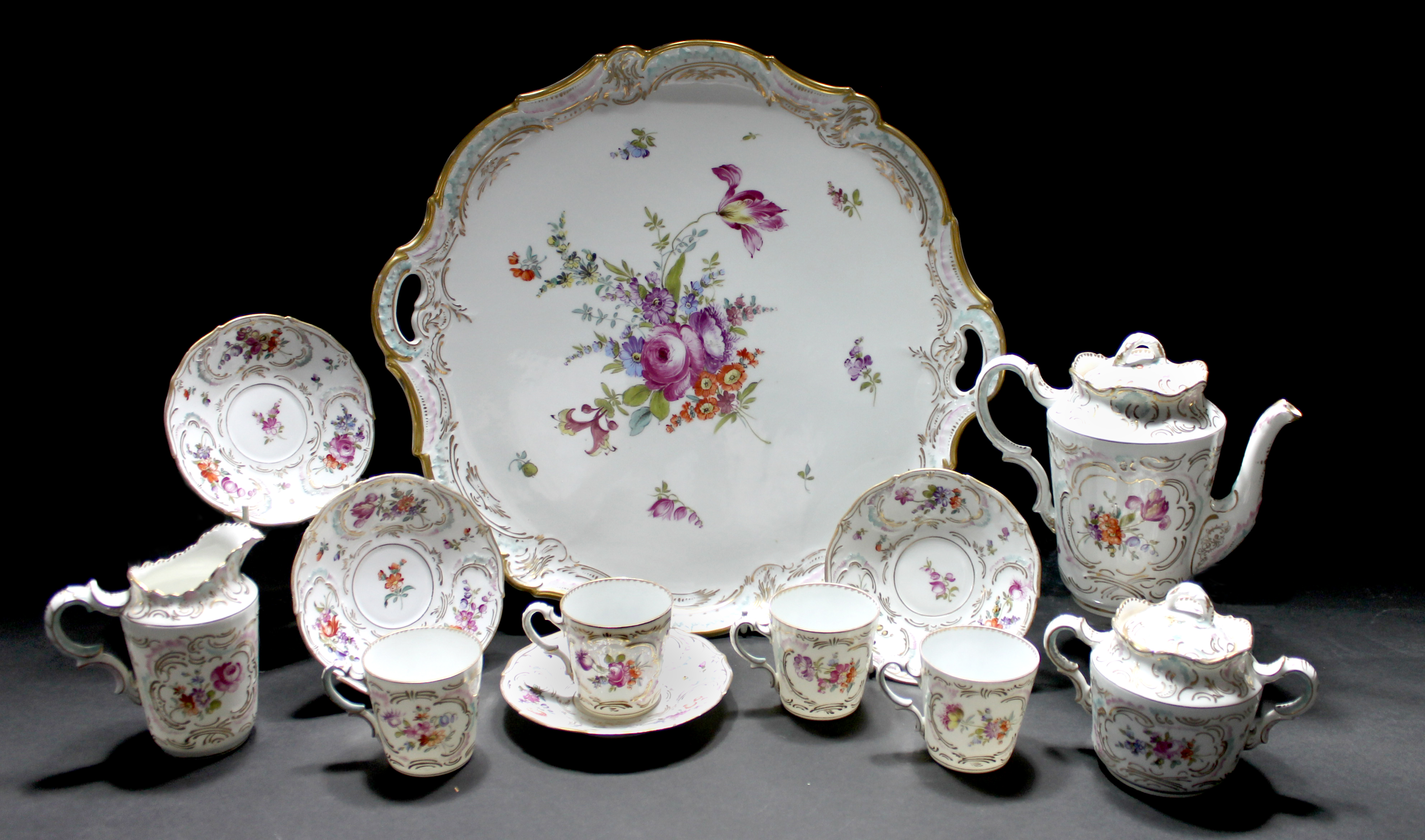 A Continental Dresden style tea service, early-mid 20th century, decorated with flowers against a