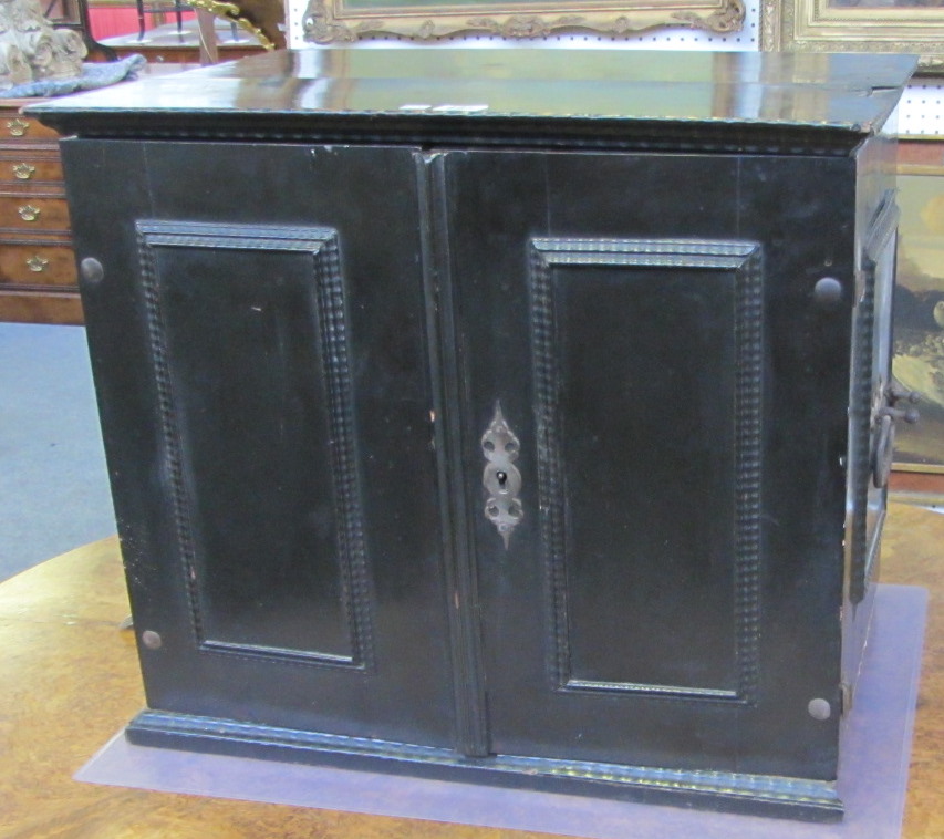 An 18th century Italian ebonised table top cabinet, the pair of doors enclosing an arrangement of