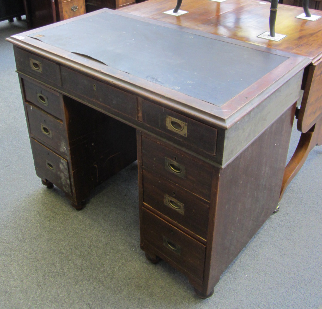 An early 20th century mahogany campaign pedestal desk with seven drawers about the knee, stamped