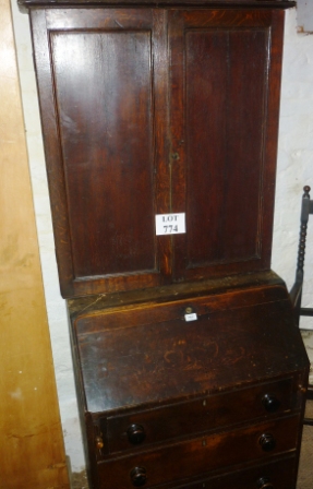 A Georgian oak bureau bookcase with panelled doors above a fall flap and fitted interior with