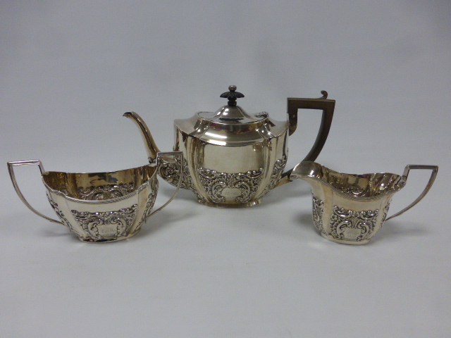 An early 20th Century silver three piece tea set with embossed foliate and scrolled decoration,