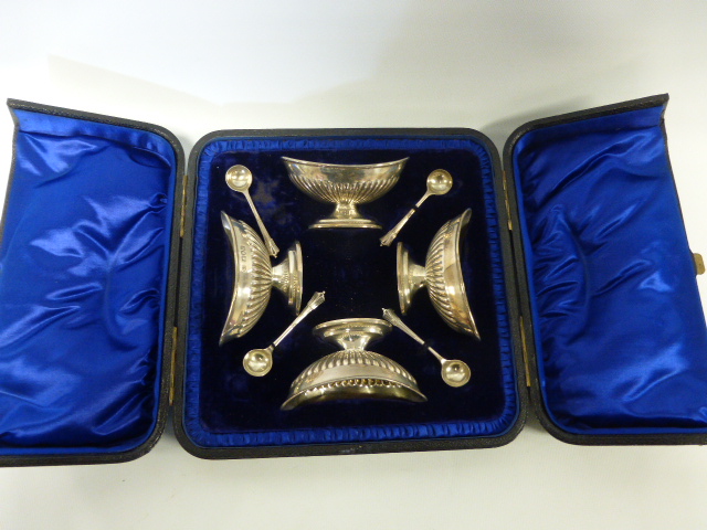 A late Victorian cased set of four silver boat shaped salts with spoons having gadrooned decoration,