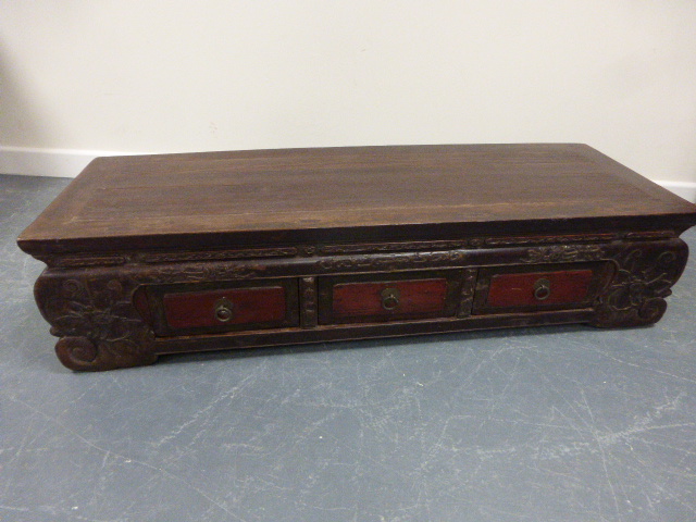 A late 19th / early 20th Century Chinese low Kang cabinet having three red lacquered drawers