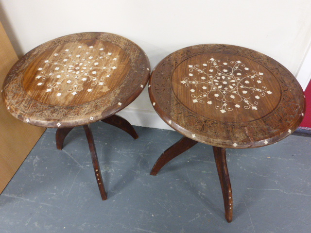 A pair of Indian tripod tables with decorative carved tops inlaid with shell, 40cms in diameter and