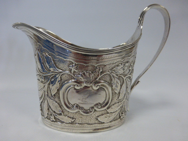 Late 18th Century George III silver jug with repoussé foliate decoration and reeded loop handle,