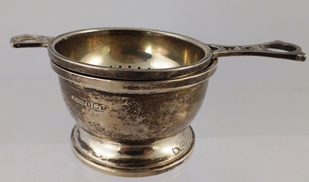 G** W** LEWIS & CO. A SILVER TEA STRAINER with pierced handle and MATCHING CRUCIBLE DRIP BOWL,