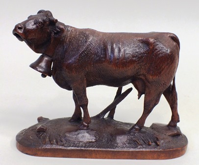 A BLACK FOREST CARVED WOOD FIGURE OF A COW on naturalistic oval plinth base, 14.5cm high