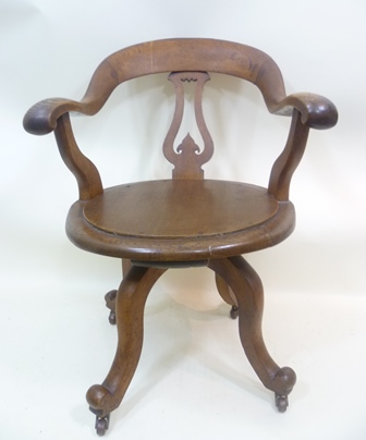 AN EARLY 20TH CENTURY SWIVEL DESK CHAIR having scroll arms & hump crest rail, later solid seat with