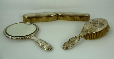 A SILVER DRESSING TABLE SET, press worked with Angelic masks comprising; a hand mirror, hair brush