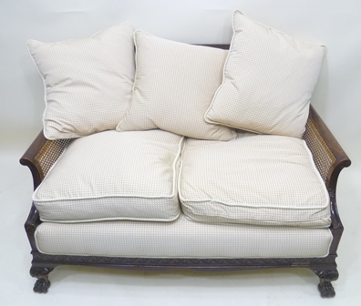 AN EARLY 20TH MAHOGANY FRAMED BERGERE TWO SEATER SETTEE having single cane back & sides, carved